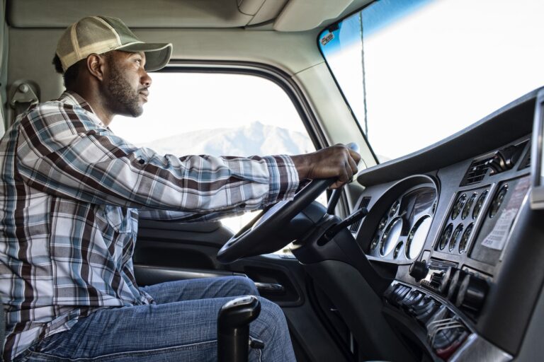 Black man truck driver in the cab of his commercial truck.