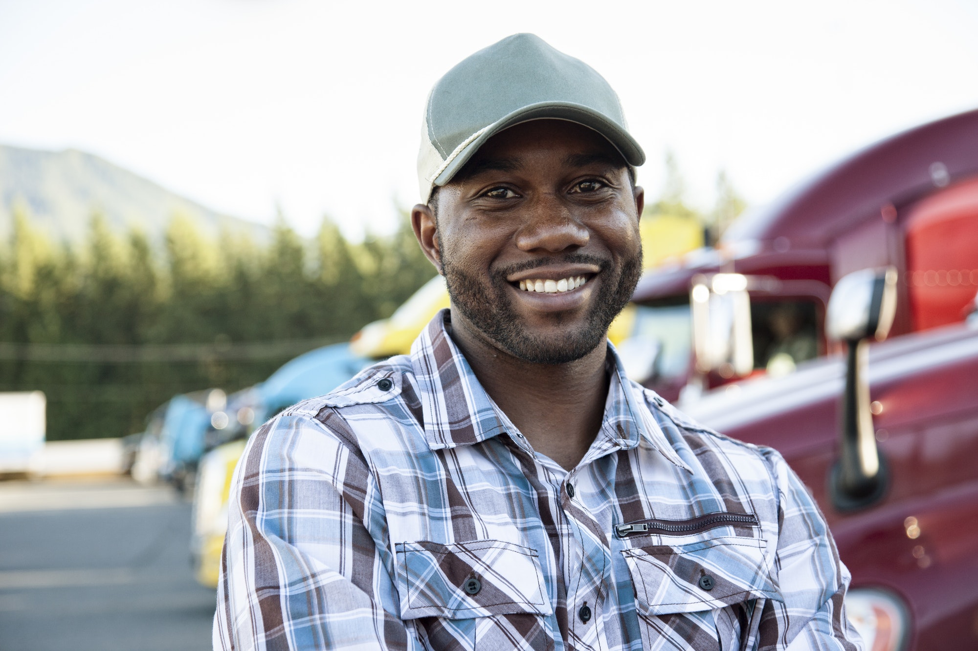 Black man truck driver near his truck parked in a parking lot at a truck stop